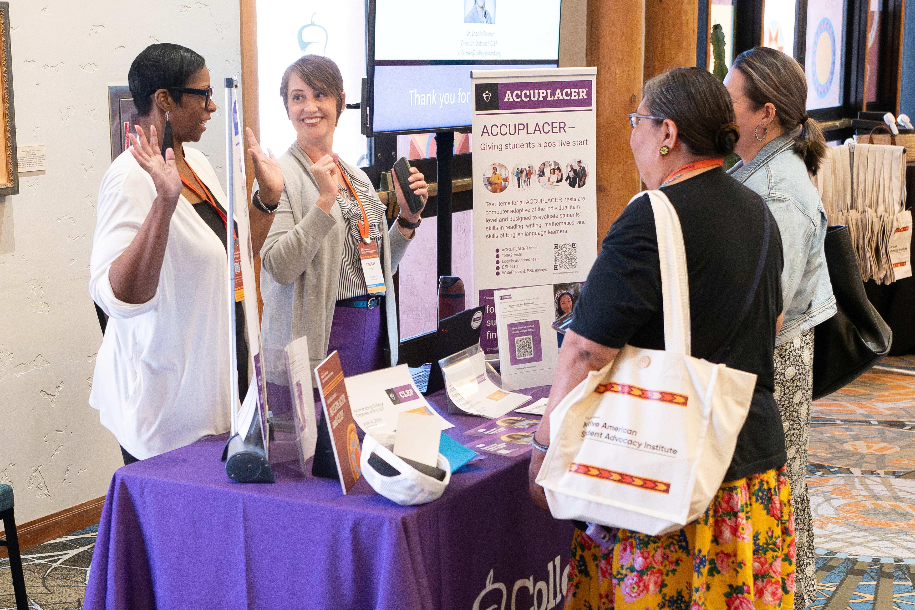 Four women having a discussion at the ACCUPLACER booth.