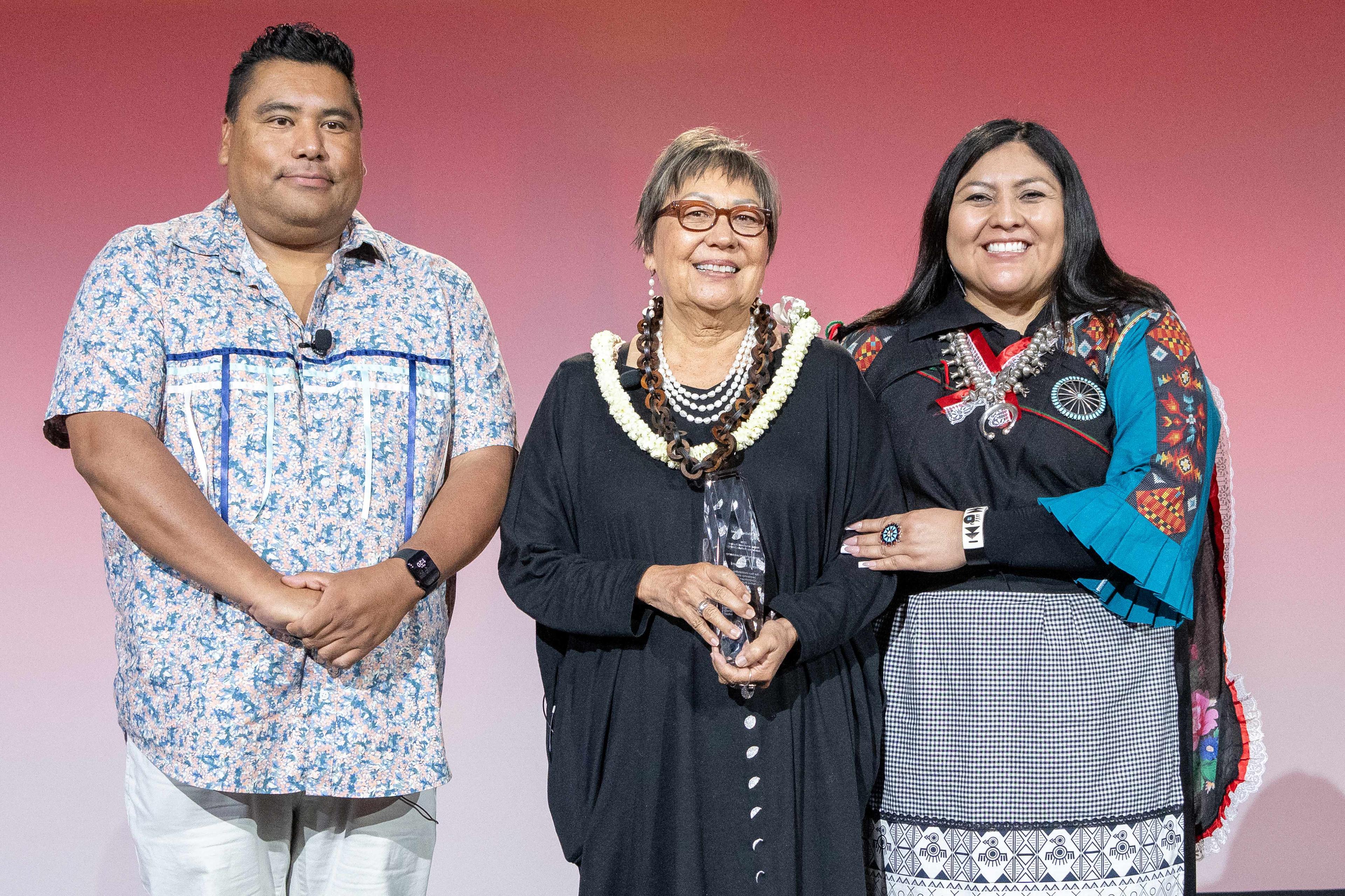 A man and a woman on stage presenting an award to a woman.