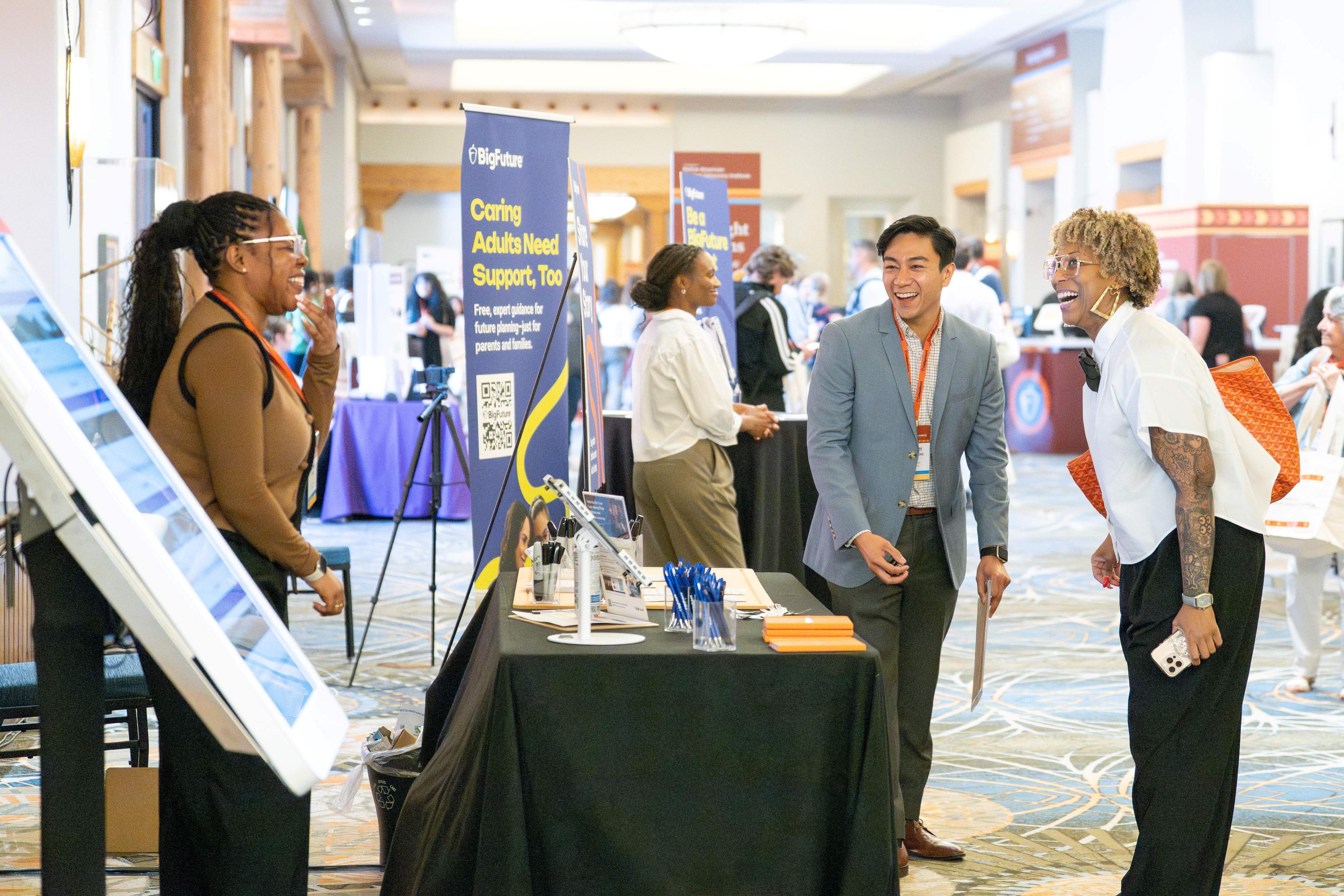 A man and two women having a discussion at the BigFuture booth.