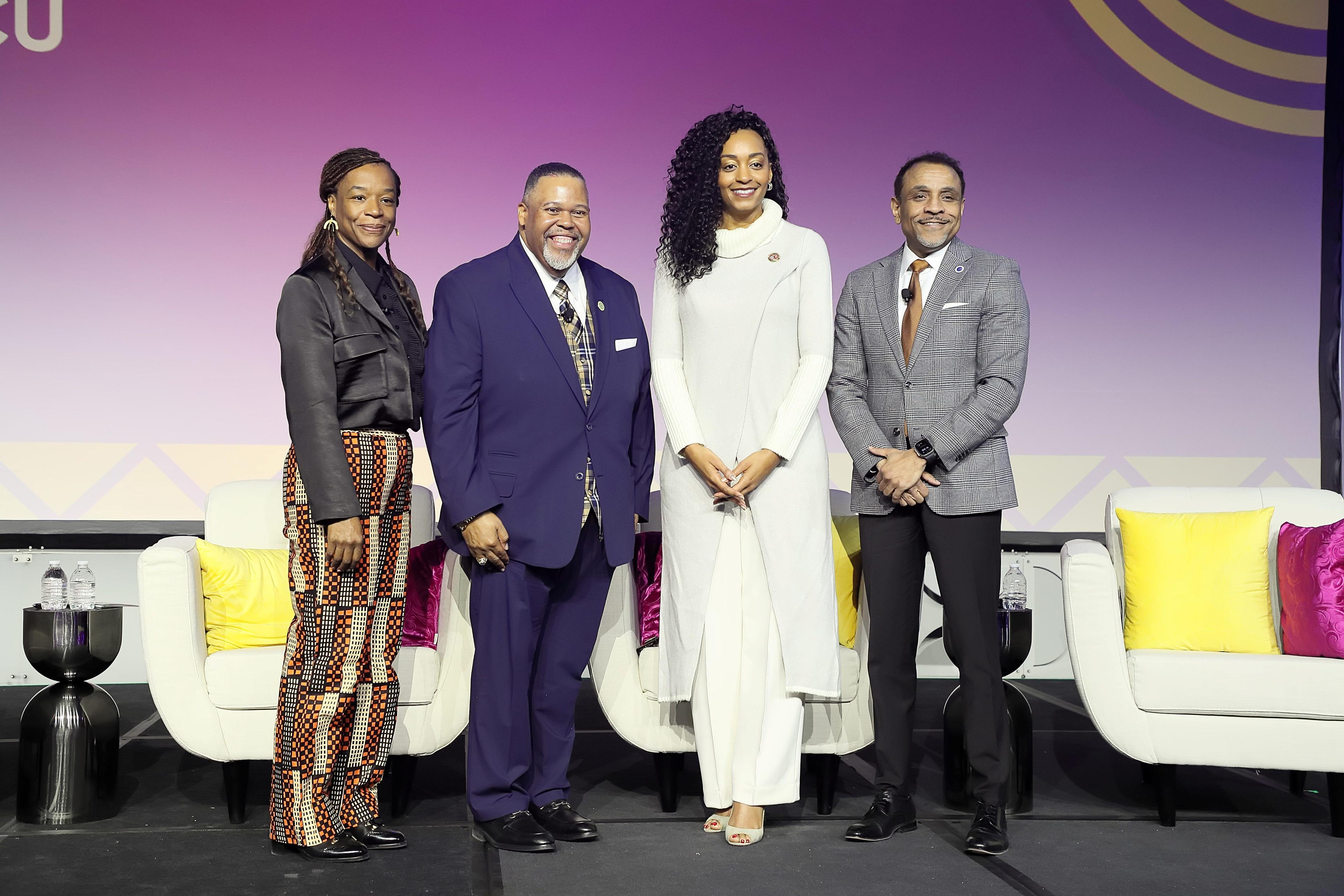 Four speakers pose for a photo on the main stage.